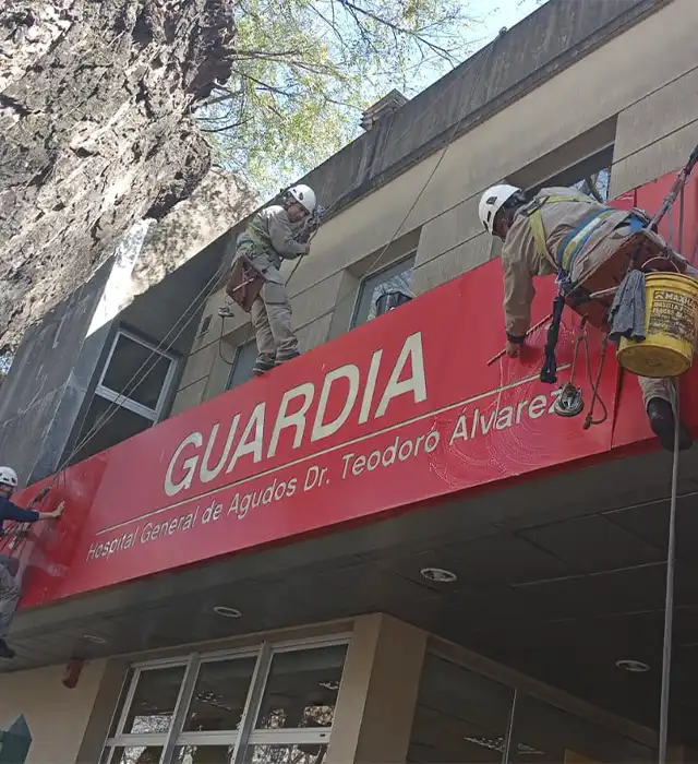 Técnico certificado realizando limpieza de vidrios en altura con arnés de seguridad